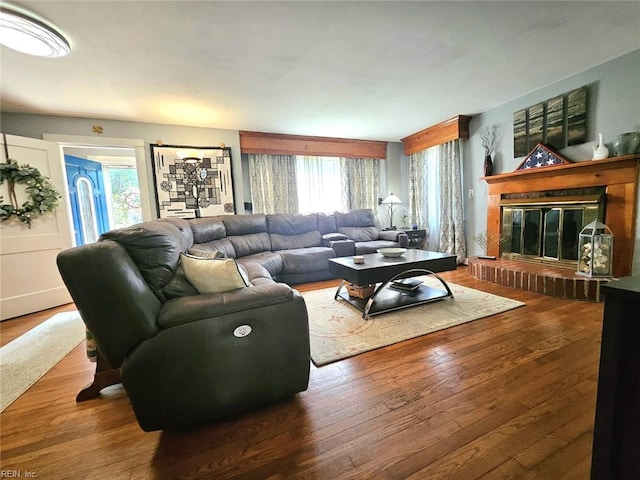 living area featuring a glass covered fireplace, a wealth of natural light, and wood finished floors