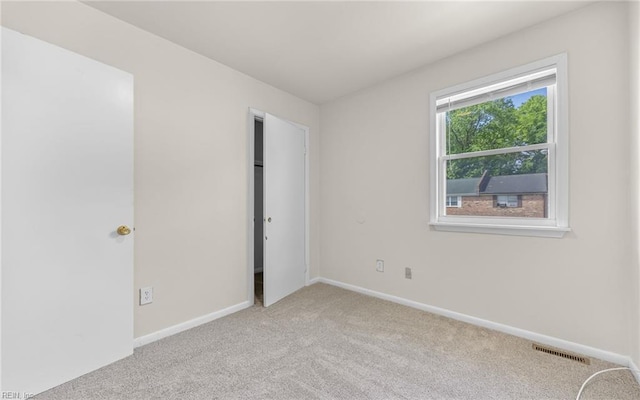 unfurnished room with light colored carpet, baseboards, and visible vents