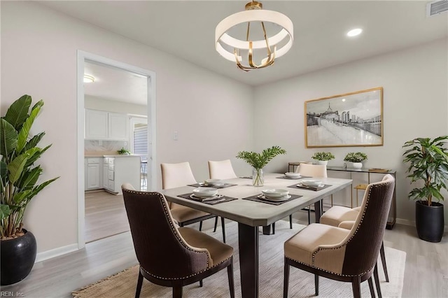 dining area featuring an inviting chandelier, baseboards, light wood finished floors, and visible vents