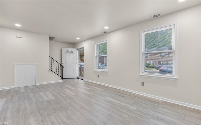 spare room with stairs, baseboards, visible vents, and light wood-type flooring