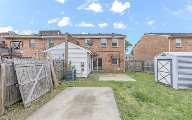 rear view of house featuring a patio, a fenced backyard, a shed, brick siding, and a yard