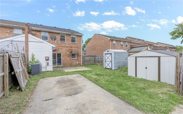 rear view of property with a patio, a fenced backyard, a shed, brick siding, and a yard