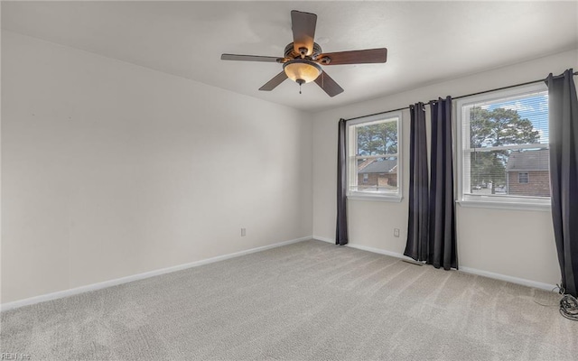 spare room with ceiling fan, light carpet, and baseboards