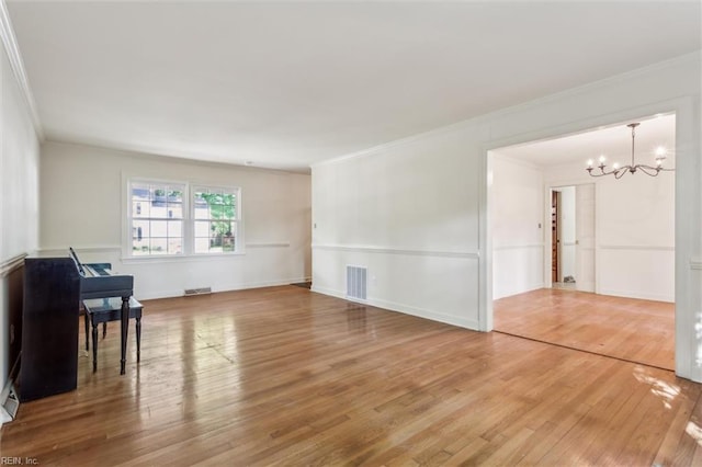 living room featuring crown molding, visible vents, wood finished floors, and a chandelier