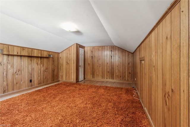 additional living space featuring baseboards, wood walls, and lofted ceiling