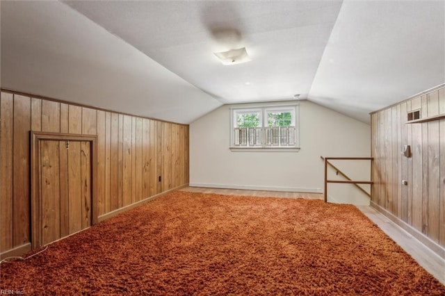 bonus room featuring wooden walls, baseboards, and vaulted ceiling