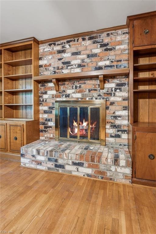 unfurnished living room with built in shelves, wood finished floors, and a fireplace