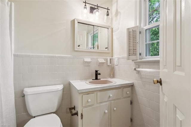 full bath featuring vanity, wainscoting, toilet, and tile walls