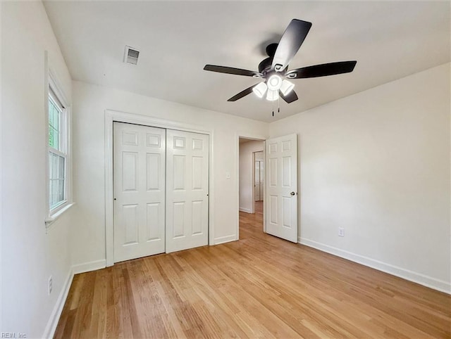 unfurnished bedroom featuring visible vents, a closet, baseboards, ceiling fan, and light wood finished floors