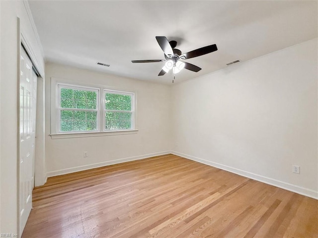 empty room featuring a ceiling fan, baseboards, visible vents, and light wood-style floors