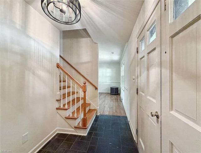 entryway featuring baseboards, a notable chandelier, and stairway