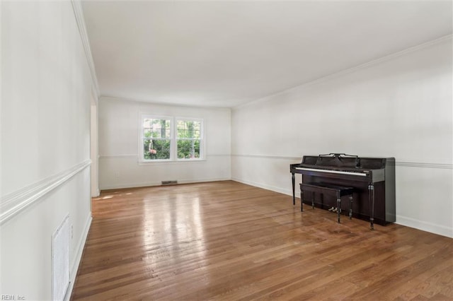 living room with baseboards, visible vents, ornamental molding, and wood finished floors