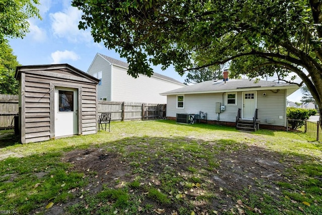 back of house with central AC, an outdoor structure, a fenced backyard, a storage unit, and entry steps