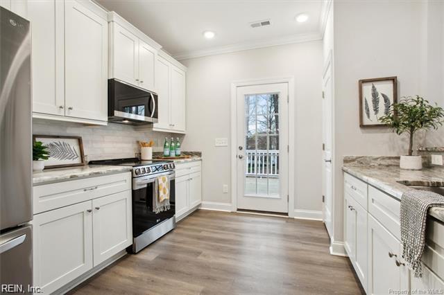 3009 Ridge Dr, Toano, VA 23168 - kitchen with crown molding, light stone countertops, white cabinetry, tasteful backsplash, and stainless steel appliances