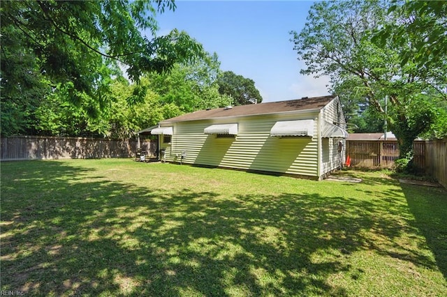 rear view of property with a lawn, a wall mounted AC, and a fenced backyard