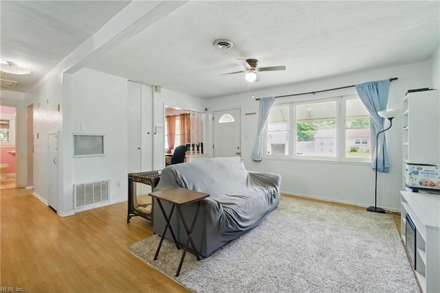 living room featuring baseboards, ceiling fan, visible vents, and wood finished floors