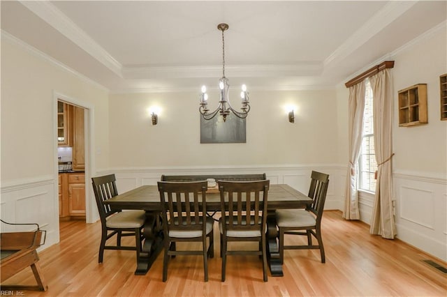dining room with a chandelier, light wood finished floors, and a decorative wall