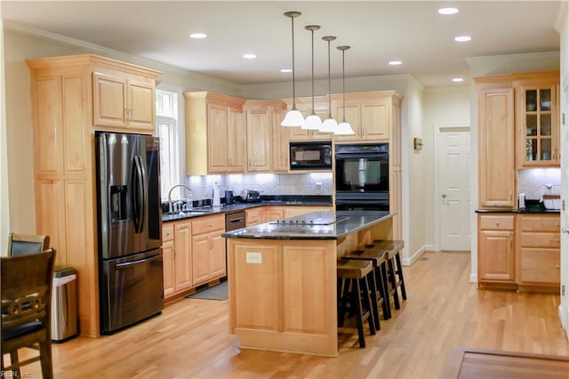 kitchen with dark countertops, a breakfast bar, black appliances, and light brown cabinets