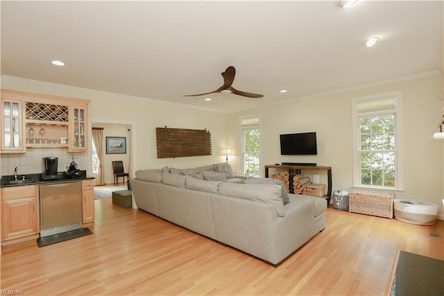 living area with crown molding, ceiling fan, light wood-style flooring, indoor wet bar, and recessed lighting