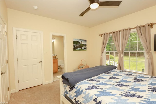 bedroom with ensuite bathroom, ceiling fan, and light colored carpet
