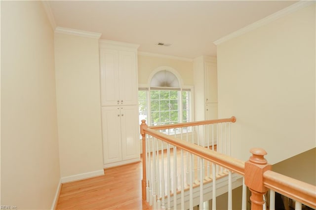 corridor with visible vents, crown molding, baseboards, an upstairs landing, and light wood-style floors