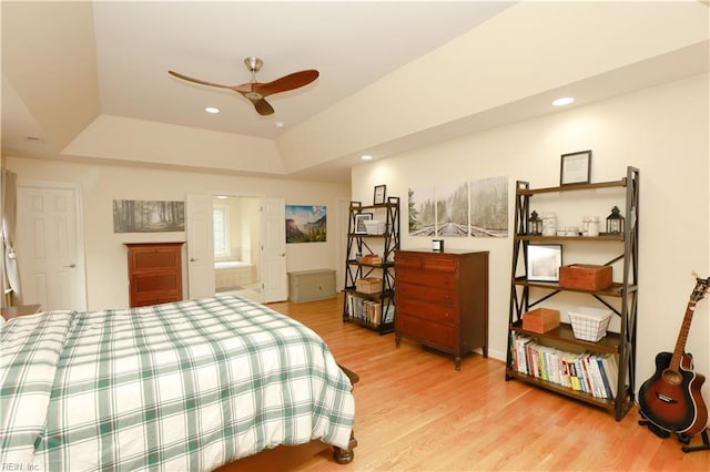 bedroom with light wood-type flooring, recessed lighting, and a tray ceiling