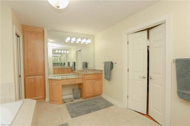 full bath featuring vanity, tile patterned flooring, baseboards, and tiled tub