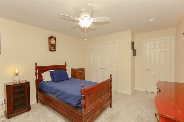 bedroom featuring baseboards, ceiling fan, light carpet, and a closet