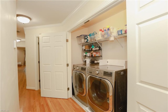 laundry area featuring laundry area, ornamental molding, light wood-style flooring, and independent washer and dryer
