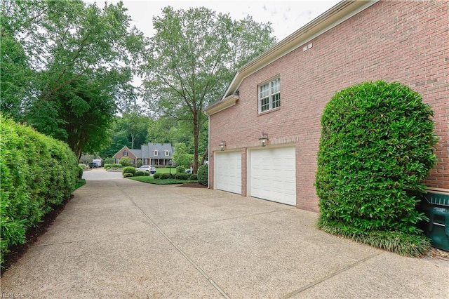 view of property exterior with a garage, concrete driveway, and brick siding