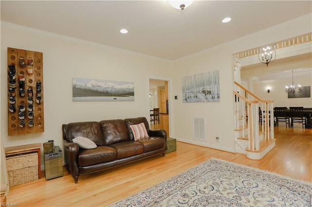 living room with ornamental molding, a notable chandelier, wood finished floors, and visible vents