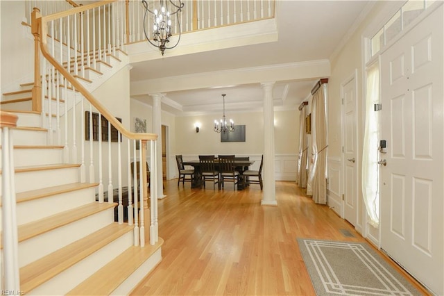 foyer entrance with crown molding, ornate columns, and a chandelier