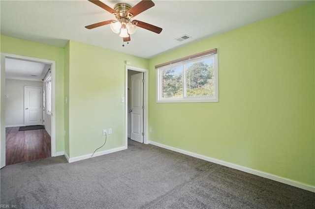 unfurnished bedroom with baseboards, dark carpet, visible vents, and ceiling fan