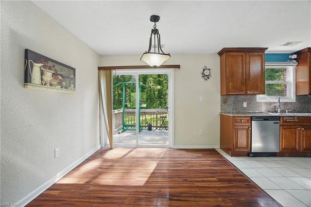 kitchen featuring a sink, backsplash, dishwasher, and a healthy amount of sunlight
