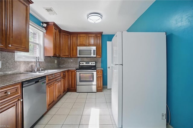 kitchen featuring visible vents, tasteful backsplash, a sink, light tile patterned floors, and stainless steel appliances