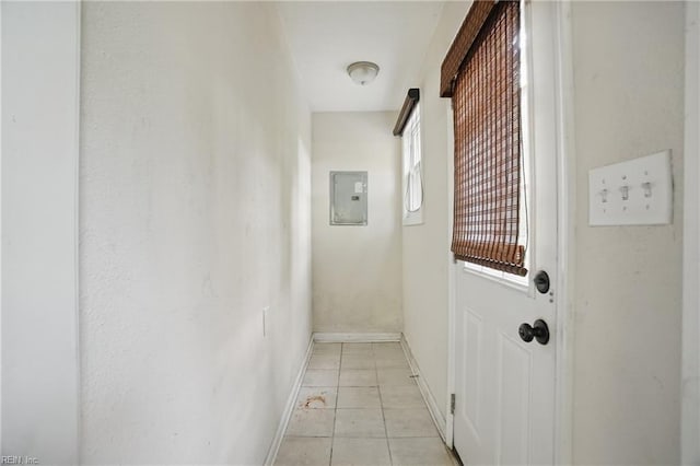 hallway featuring baseboards, electric panel, and light tile patterned flooring
