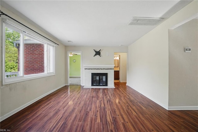 unfurnished living room with baseboards, a fireplace with flush hearth, wood finished floors, and visible vents