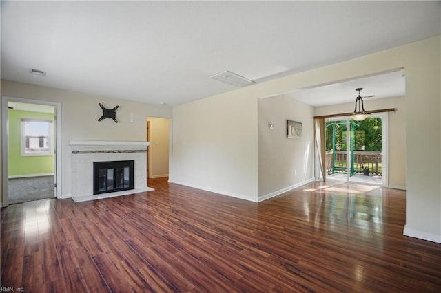 unfurnished living room featuring baseboards, visible vents, a fireplace with flush hearth, and wood finished floors