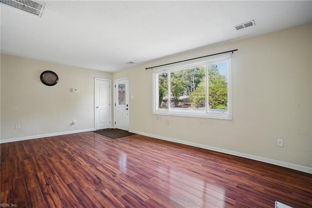 interior space with baseboards, wood finished floors, and visible vents