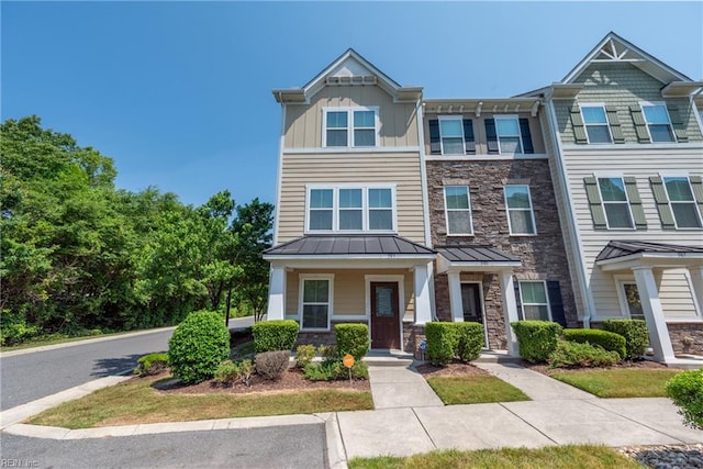 townhome / multi-family property with board and batten siding, metal roof, stone siding, and a standing seam roof
