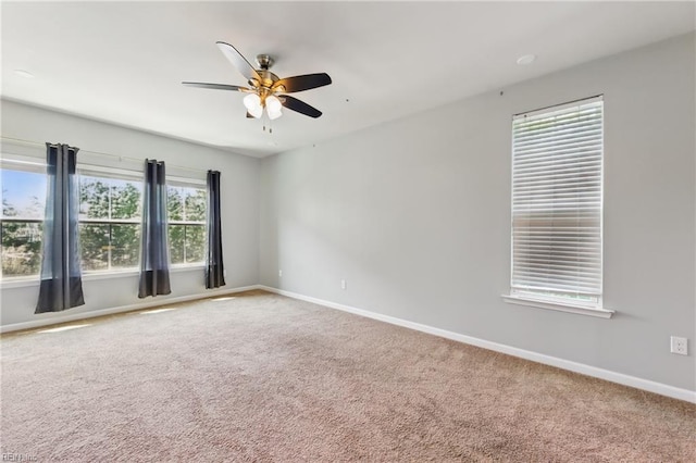 carpeted empty room featuring baseboards and a ceiling fan