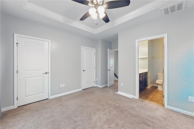 unfurnished bedroom featuring visible vents, baseboards, ornamental molding, a tray ceiling, and carpet flooring