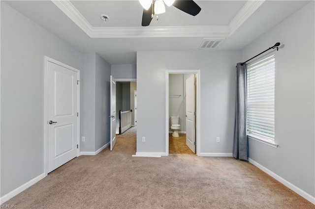 unfurnished bedroom featuring carpet floors, visible vents, ornamental molding, and a raised ceiling
