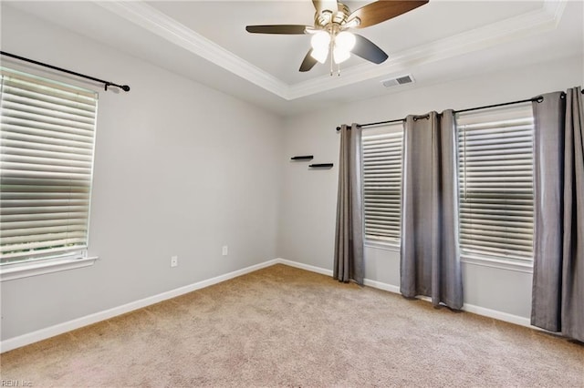 unfurnished room featuring visible vents, crown molding, a raised ceiling, baseboards, and light carpet