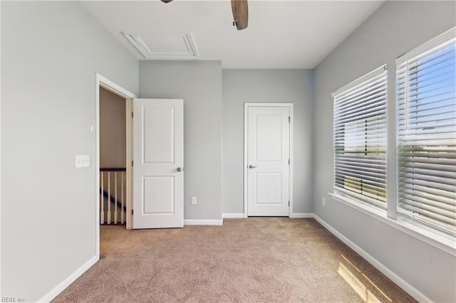 unfurnished bedroom featuring baseboards, attic access, carpet, and ceiling fan