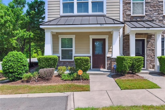 doorway to property with a standing seam roof, metal roof, and stone siding
