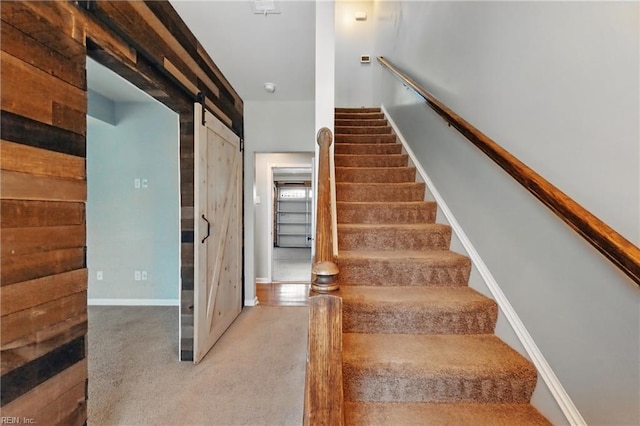 stairs featuring baseboards, a barn door, and carpet