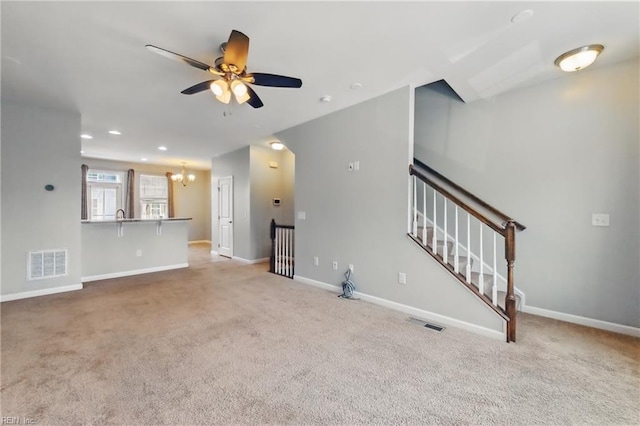 unfurnished living room with baseboards, visible vents, carpet, and ceiling fan with notable chandelier