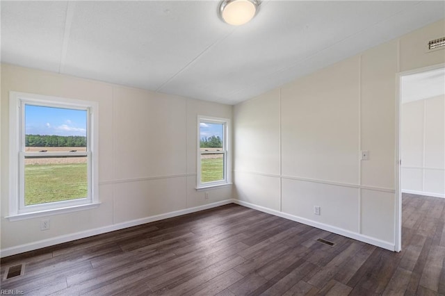 spare room with baseboards, visible vents, wood finished floors, and a wealth of natural light