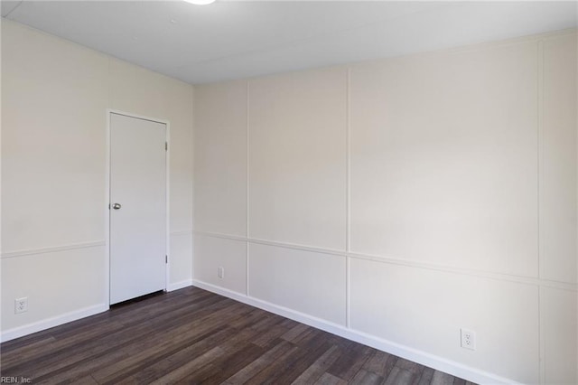 spare room with dark wood-style flooring and baseboards